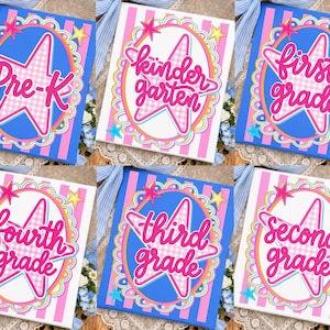 May include: A collection of six rectangular signs featuring a central pink gingham star inside a scalloped oval frame. Each sign displays a school grade level in pink cursive text, including Pre-K, kindergarten, first, second, third, and fourth grade.
