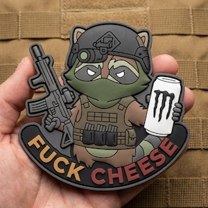 May include: A tactical morale patch featuring a cartoon raccoon wearing a helmet, night vision goggles, and a plate carrier. The raccoon holds a rifle in one hand and a white energy drink can in the other. The text FUCK CHEESE is printed below.