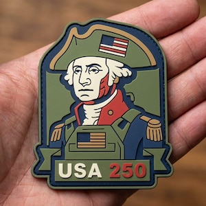 May include: A rectangular morale patch featuring a stylized illustration of George Washington in a tricorn hat with an American flag, wearing a military uniform with a plate carrier, and the text USA 250 in white and red on a dark blue and olive background.