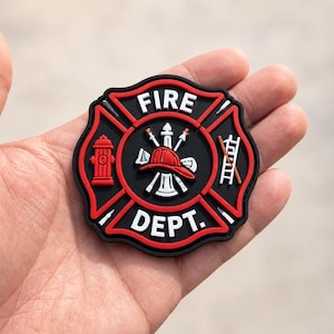 May include: A circular black and red rubberized patch featuring the text FIRE DEPT. in white lettering. The center displays a red firefighter helmet, a fire hydrant, and a ladder icon, all rendered in a raised, molded design with bold colors.