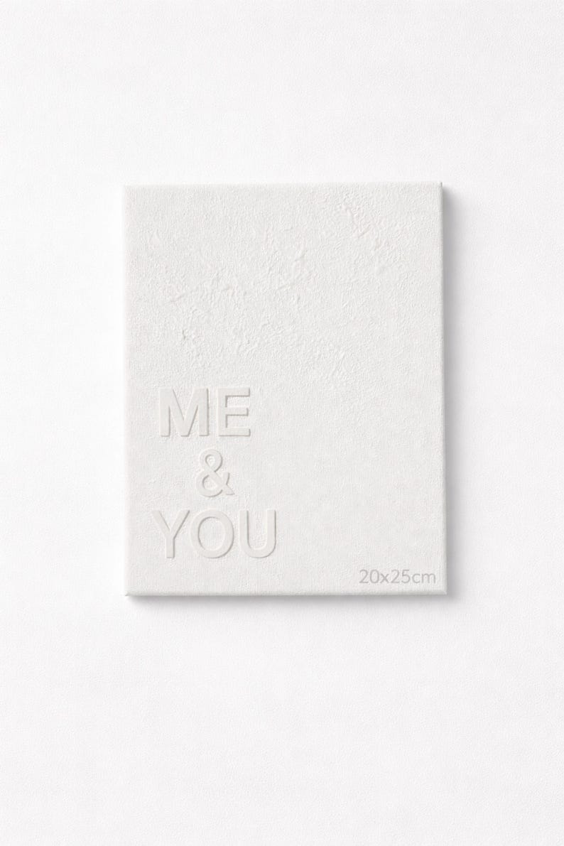 May include: A rectangular white canvas featuring the embossed text ME & YOU in a clean sans-serif font. The surface has a subtle textured finish, and the bottom right corner displays the printed dimensions of 20x25 cm for this wall art piece.