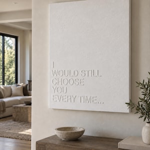 Könnte beinhalten: Ein rechteckiges, weißes Wandkunstwerk mit erhabenen, geprägten Buchstaben, die den Text I WOULD STILL CHOOSE YOU EVERY TIME... bilden. Die Oberfläche hat eine matte Textur und der Text ist auf der linken Seite der Leinwand ausgerichtet.