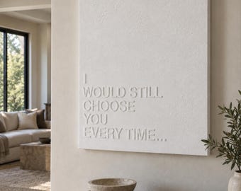 May include: A rectangular white wall art piece featuring raised, embossed lettering that reads I WOULD STILL CHOOSE YOU EVERY TIME... The surface has a textured, matte finish, and the text is aligned to the left side of the canvas.