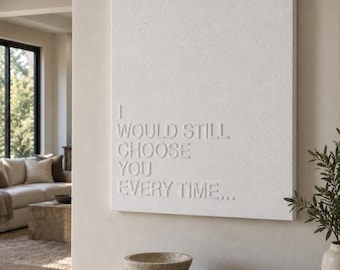 May include: A rectangular white wall art piece featuring raised, embossed lettering that reads I WOULD STILL CHOOSE YOU EVERY TIME... The surface has a textured, matte finish, and the text is aligned to the left side of the canvas.