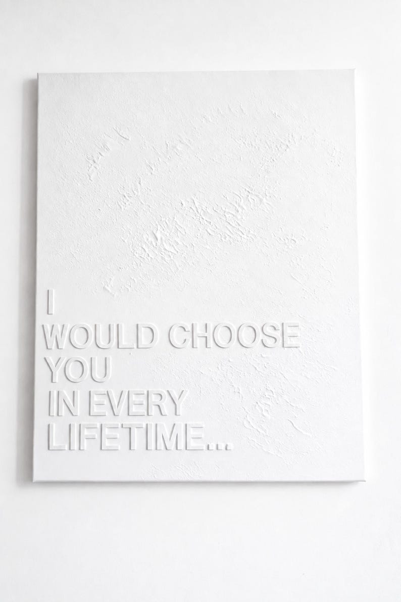 May include: A rectangular white canvas featuring a textured surface with raised white lettering that reads: I WOULD CHOOSE YOU IN EVERY LIFETIME... The artwork is monochromatic, with the text standing out against the subtle, uneven relief of the background.