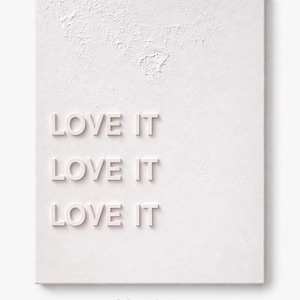 May include: A white rectangular wall art piece with a textured surface featuring the repeated text LOVE IT in raised lettering. The artwork includes printed text at the bottom indicating dimensions of 30x40cm for the physical piece.
