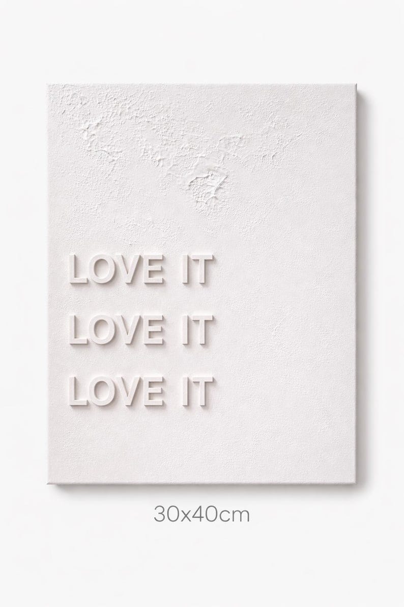 May include: A white rectangular wall art piece with a textured surface featuring the repeated text LOVE IT in raised lettering. The artwork includes printed text at the bottom indicating dimensions of 30x40cm for the physical piece.