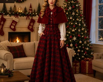 May include: A long-sleeved dress featuring a red and black plaid pattern, a button-down bodice, and a full-length skirt. The dress is paired with a deep red velvet capelet that fastens at the neck with a large matching velvet bow.