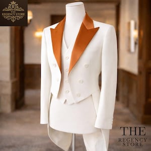 Op de afbeelding: Een formeel wit pak met een oranje satijnen revers en vest. De dubbelbreasted jas heeft twee rijen knopen. Het pak wordt op een mannequin getoond. Het logo van The Regency Store staat linksboven en rechtsonder.