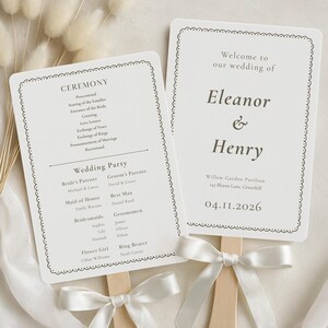 May include: Two rectangular wedding programme fans with rounded corners and a decorative scalloped border. Each fan features dark grey text on a white background, attached to a wooden handle with a white satin ribbon bow tied at the base.