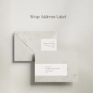 Op de afbeelding: Twee lichtgrijze enveloppen en een wikkeladreslabel worden weergegeven tegen een neutrale achtergrond. Het label en de enveloppen hebben een elegant lettertype en de tekst "Wrap Address Label". De enveloppen zijn geadresseerd aan "Eleanor & Henry" en "Emily & Daniel Hart".