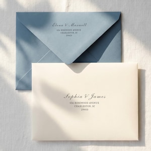 Op de afbeelding: Twee enveloppen, &eacute;&eacute;n lichtblauw en &eacute;&eacute;n cr&egrave;mekleurig, worden getoond. De lichtblauwe envelop is open en onthult de binnenkant. Beide enveloppen hebben elegante zwarte tekst: namen, adres en postcode. De tekst luidt "Elena V Maxwell" en "Sophia & James."