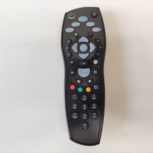 Può includere: Un telecomando per televisione Sky di colore nero dotato di un pad di navigazione centrale con tasto OK, tastierino numerico, controlli di riproduzione e quattro tasti colorati. Il dispositivo include un tasto di accensione e tasti menu.