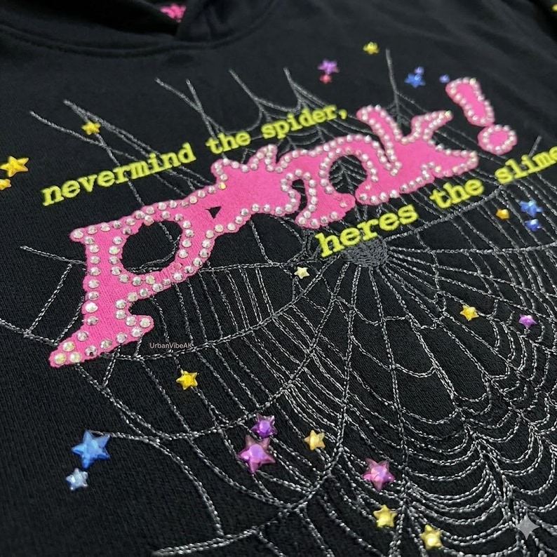 Peut inclure: Sweat &agrave; capuche noir avec un motif "POOK!" rose orn&eacute; de strass, une toile d'araign&eacute;e et le texte "nevermind the spider, heres the slime". Le motif comprend des &eacute;toiles et des pierres pr&eacute;cieuses.