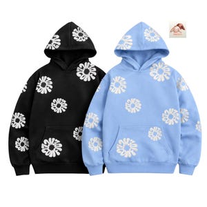 May include: Two hooded sweatshirts, one black and one light blue, each adorned with white floral designs. The sweatshirts have a front pocket and a drawstring hood. The floral pattern is repeated across the front, sleeves, and hood.