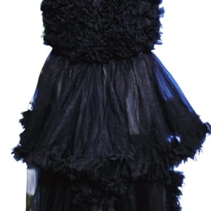 Może przedstawiać: Czarna suknia wieczorowa z warstwową tiulową spódnicą i marszczonym stanikiem. Suknia jest prezentowana na białym manekinie, prezentując jej elegancki design i fakturę. Ciemny kolor i szczegóły sugerują strój formalny.