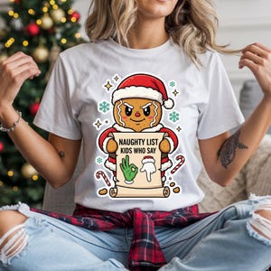 Könnte beinhalten: Weißes T-Shirt mit einem Lebkuchenmann, der einen Weihnachtsmannhut trägt und eine Schriftrolle mit der Aufschrift "NAUGHTY LIST KIDS WHO SAY" hält. Das Design umfasst Schneeflocken, Zuckerstangen und Handgesten.