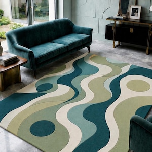 Puede incluir: Una alfombra estampada con un diseño retro en un salón. La alfombra presenta formas fluidas en verde azulado, verde y crema. La alfombra está colocada en una habitación con un sofá verde azulado y un mueble negro. El diseño de la alfombra recuerda a los años 70.