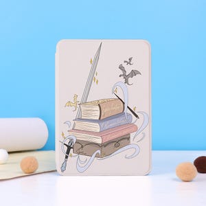 May include: A rectangular e-reader case with a light beige background featuring a stack of four books, a sword, a quill, and flying dragons. The books are labeled with the text Epic Fantasy, Romantasy, and Romantasy Literary in cursive script.