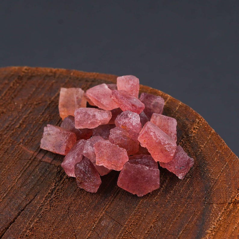 Puede incluir: Una colecci&oacute;n de peque&ntilde;os fragmentos de piedras preciosas en bruto, transl&uacute;cidas y de color rojo rosado, con formas irregulares y angulosas y superficies facetadas. Las piedras muestran varios tonos de rosa intenso y coral claro.