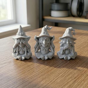 Peut inclure: Trois figurines grises en pierre représentant des sorcières assises en rang. La première sorcière se couvre les yeux, la deuxième se couvre les oreilles et la troisième se couvre la bouche. Chaque figurine porte un chapeau pointu et une robe.
