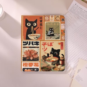 Może przedstawiać: Dekoracyjny notatnik z kolażem ilustracji w stylu vintage. Grafika zawiera czarne koty jedzące ramen, łowiące ryby i inne sceny, z japońskim tekstem i obrazem kwiatowym. Notatnik ma kremowe tło.