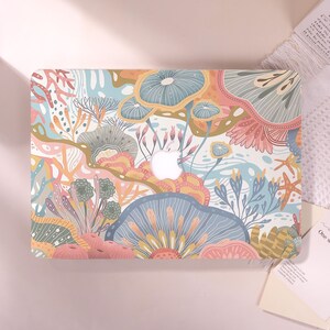 May include: A laptop case featuring a colorful, abstract design of coral and sea plants in shades of blue, pink, yellow, and green. The Apple logo is visible in the center. The case has a smooth finish and a vibrant, artistic aesthetic.