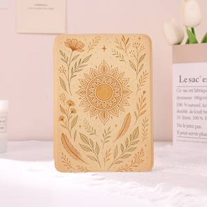 May include: A rectangular tablet case in a light beige color featuring a central mandala design surrounded by various botanical illustrations including flowers, leaves, and feathers in a darker brown line art style with small star accents.