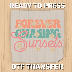 May include: A beige DTF transfer with the words "FOREVER CHASING SUNSETS" in orange, teal, and pink, decorated with daisy and sun graphics. The words "READY TO PRESS" and "DTF TRANSFER" are at the top and bottom.
