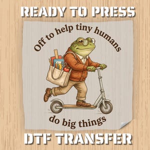 May include: A whimsical illustration features a frog riding a scooter, wearing glasses and a sweater, with a tote bag filled with school supplies. The text reads "Off to help tiny humans do big things" and "READY TO PRESS DTF TRANSFER".
