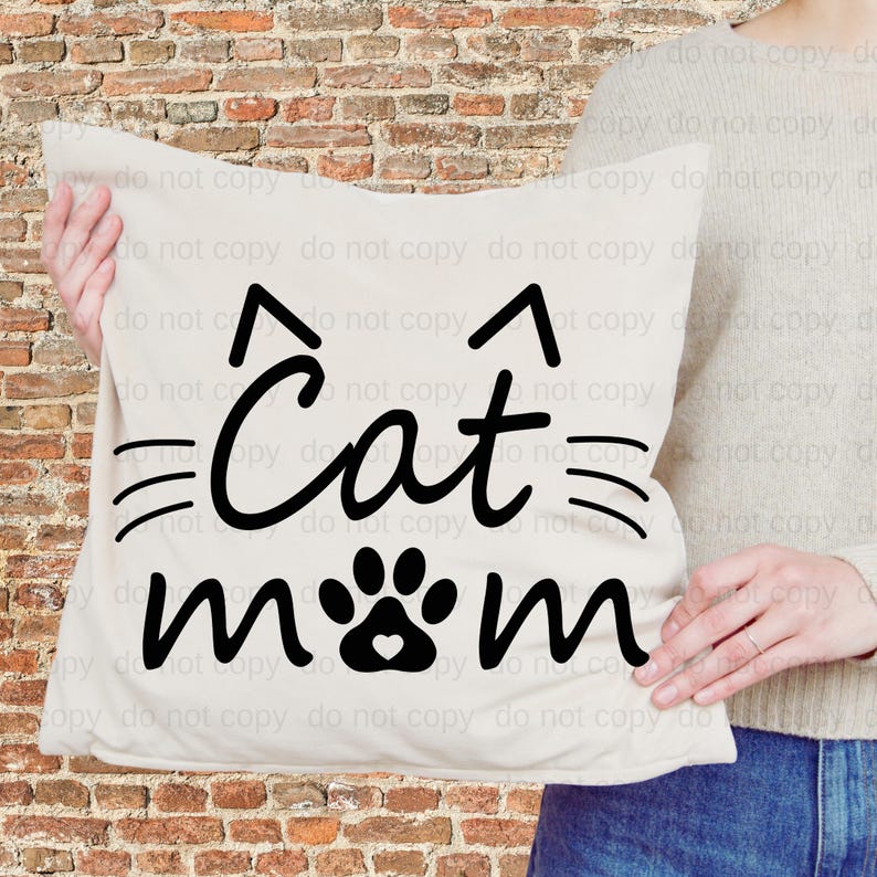 A person is holding a white pillow with the text "Cat mom" printed on it, which appears to be a cat-themed design.