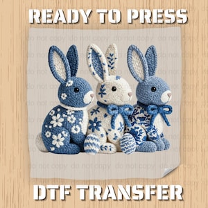 May include: Three blue and white bunny rabbit DTF transfers. The bunnies have floral patterns and bows. The text "READY TO PRESS" and "DTF TRANSFER" are at the top and bottom of the image.