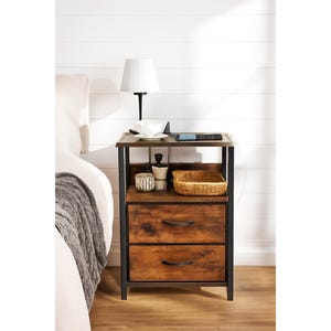 May include: A two-drawer nightstand with a dark brown wood finish and black metal frame. The nightstand has a top shelf with a lamp, a small bowl, and a book. The bottom shelf has a woven basket and decorative items.