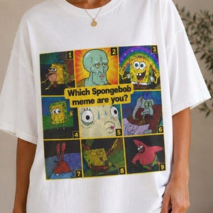 May include: A white short-sleeved t-shirt featuring a graphic grid of nine Spongebob Squarepants character memes. The center text reads "Which Spongebob meme are you?" with each square numbered one through nine, showcasing various colorful cartoon expressions.
