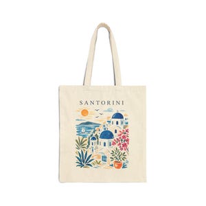 A cream tote bag with a colourful illustration of Santorini, Greece. The design features blue-domed buildings, the sea, and the word "SANTORINI".