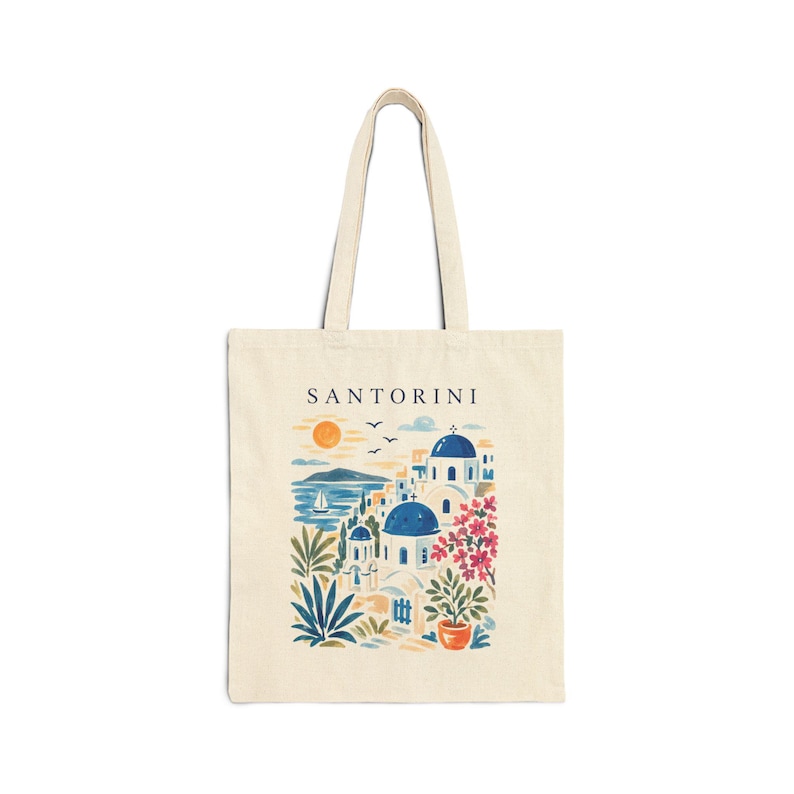 A cream tote bag with a colourful illustration of Santorini, Greece. The design features blue-domed buildings, the sea, and the word "SANTORINI".
