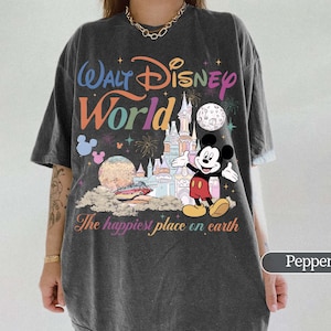 May include: Pepper-colored t-shirt featuring a colorful Walt Disney World graphic. The design includes the park's logo, a castle, Mickey Mouse, and the phrase "The happiest place on earth."