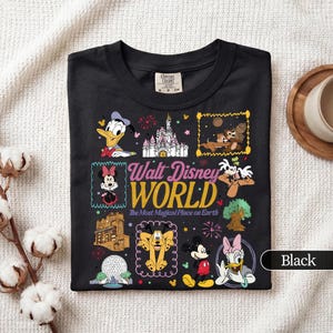 May include: Black t-shirt featuring a colorful graphic of various Disney characters and landmarks. The text "Walt Disney World" is prominently displayed, along with the phrase "The Most Magical Place on Earth."