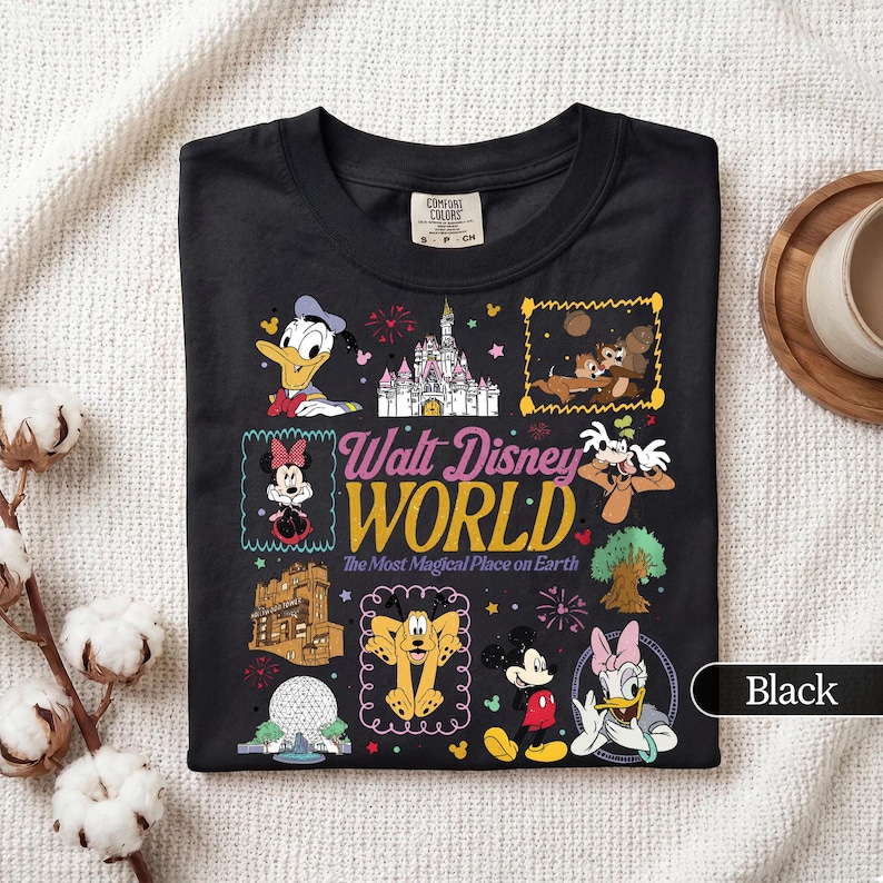 May include: Black t-shirt featuring a colorful graphic of various Disney characters and landmarks. The text "Walt Disney World" is prominently displayed, along with the phrase "The Most Magical Place on Earth."