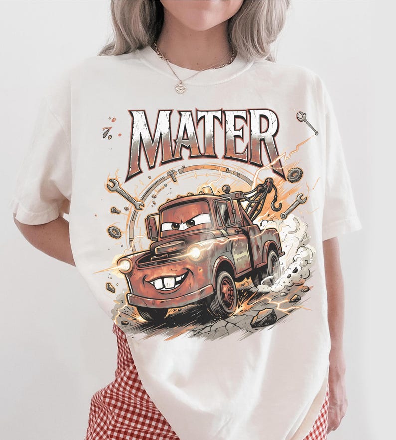 May include: Cream-colored t-shirt featuring a cartoon illustration of Mater, the tow truck from the movie Cars. The design includes the word "MATER" in a distressed font, along with wrenches and other mechanical elements.
