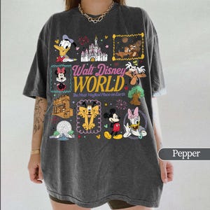 May include: Pepper-colored t-shirt featuring a colorful graphic of various Disney characters and the words "Walt Disney World." The design includes images of Mickey Mouse, Minnie Mouse, Donald Duck, and other beloved characters.