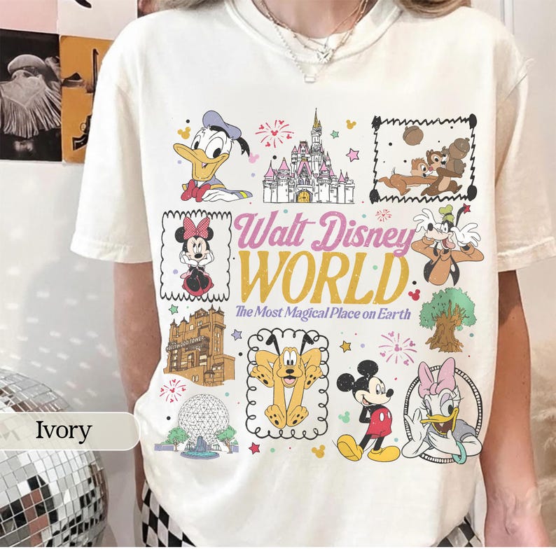 May include: Ivory-colored t-shirt featuring a colorful graphic of various Disney characters and landmarks. The design includes Donald Duck, Minnie Mouse, Chip and Dale, and the Cinderella Castle. Text reads "Walt Disney World" and "The Most Magical Place on Earth."