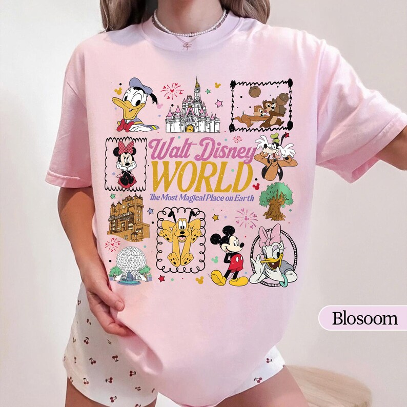 May include: A light pink t-shirt featuring various Disney characters and landmarks. The shirt has the words "Walt Disney World" and "The Most Magical Place on Earth" printed on it. The shirt is a short-sleeved, crew neck style.