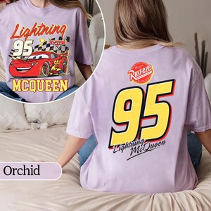 May include: Orchid-coloured t-shirt featuring Lightning McQueen from the Cars movie. The front graphic shows McQueen with the text "Lightning 95 McQueen". The back displays a large "95" and "Lightning McQueen" text.