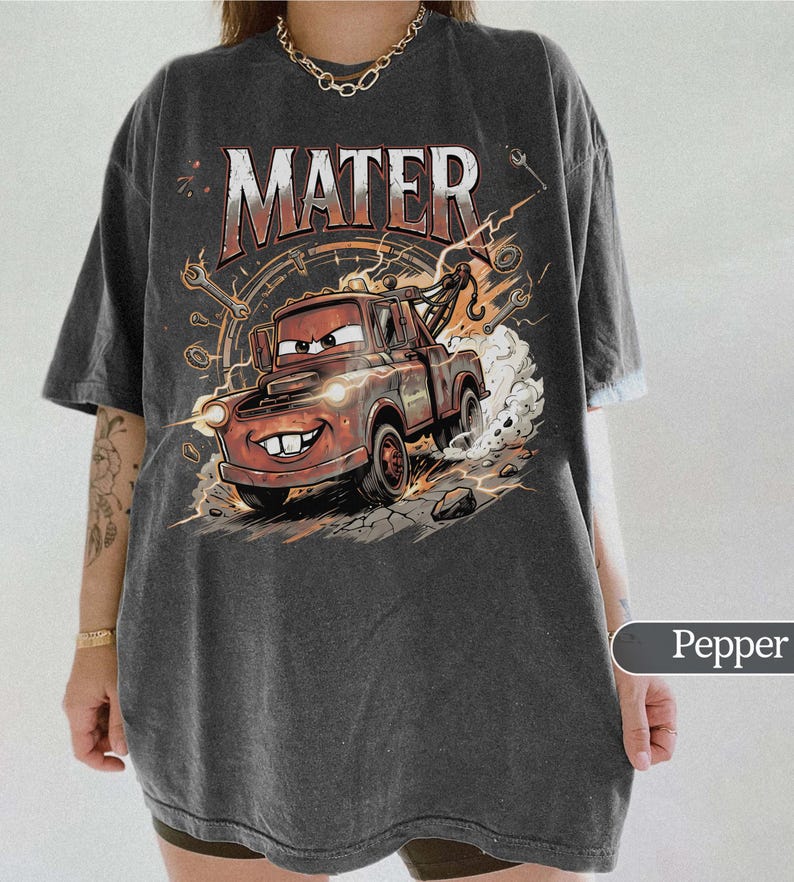 May include: Dark gray t-shirt featuring a cartoon image of Mater from the movie Cars. The graphic includes the word "MATER" in a distressed font, a smiling Mater, and a background of gears and lightning.