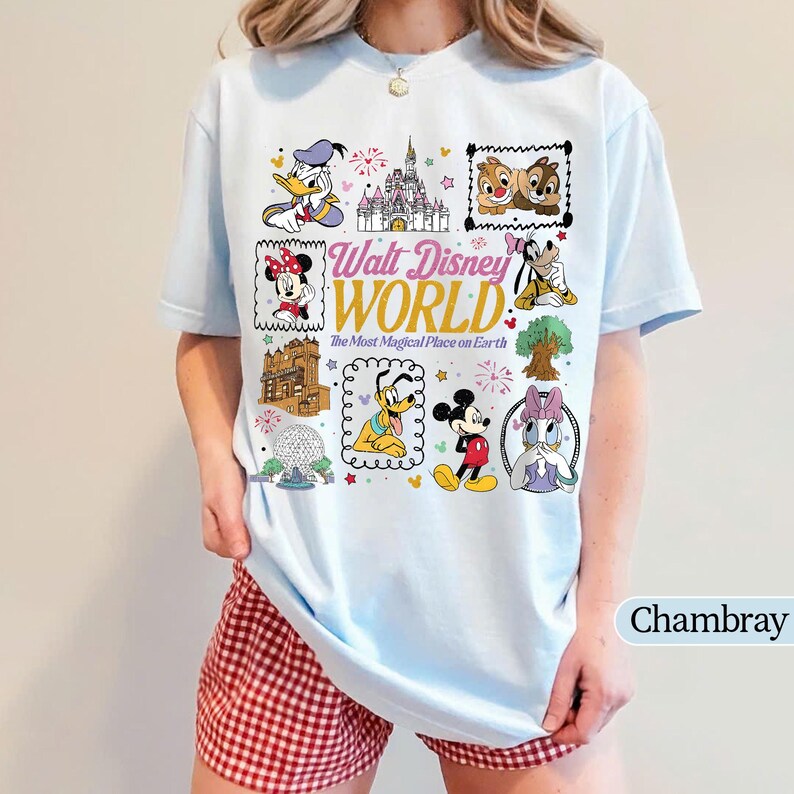 K&ouml;nnte beinhalten: Hellblaues T-Shirt mit einem farbenfrohen Aufdruck verschiedener Disney-Charaktere und Wahrzeichen. Das Design umfasst Donald Duck, Mickey Mouse und den Text "Walt Disney World: The Most Magical Place on Earth."