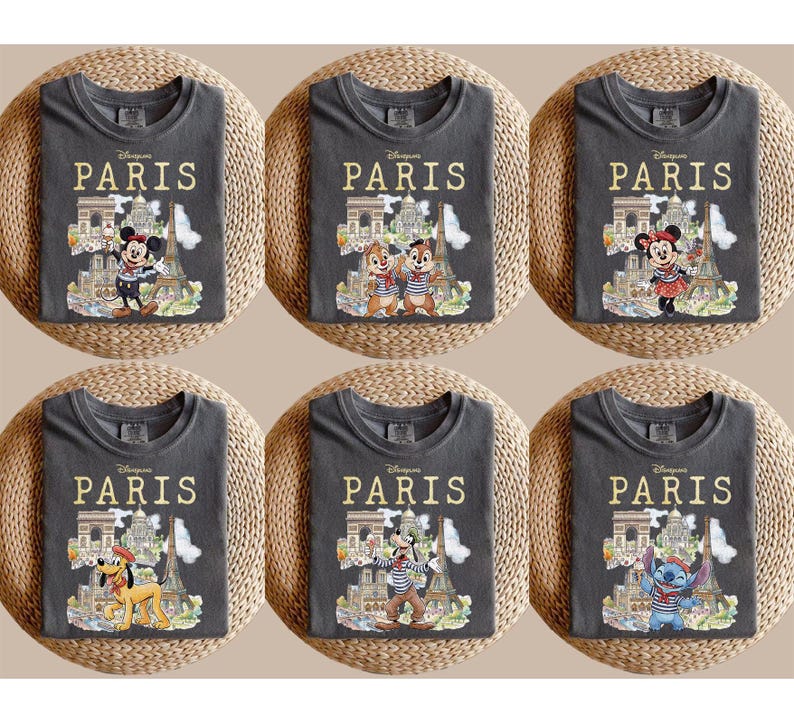 K&ouml;nnte beinhalten: Sechs anthrazitfarbene T-Shirts mit Disney-Figuren in Paris. Jedes Shirt hat den Schriftzug "PARIS" in Gold &uuml;ber einer Illustration des Eiffelturms und anderer Wahrzeichen. Zu den Figuren geh&ouml;ren Micky Maus, Minnie Maus, Chip und Chap, Pluto und Stitch.