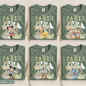K&ouml;nnte beinhalten: Sechs olivgr&uuml;ne T-Shirts mit dem Wort "PARIS" in goldener Schrift. Jedes Shirt zeigt eine andere Disney-Figur vor Pariser Wahrzeichen wie dem Eiffelturm und dem Arc de Triomphe. Figuren sind Minnie Maus, Pluto, Chip und Chap, Micky Maus, Goofy und Stitch.