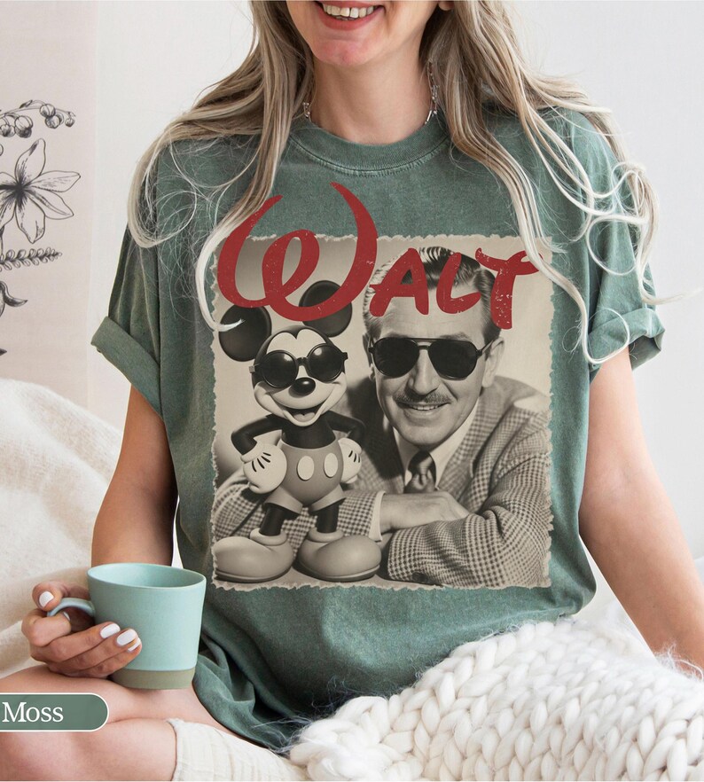 May include: Moss green t-shirt featuring a vintage-style graphic of Mickey Mouse wearing sunglasses and Walt Disney. The word "WALT" is printed in red above the image. The shirt is a relaxed fit.