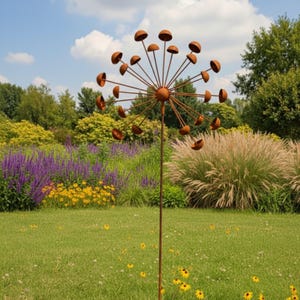 May include: A tall, rusty metal garden sculpture, reminiscent of a dandelion. The sculpture has a central sphere with radiating stems, each holding a half-sphere. It stands in a grassy garden, with colourful flowers and greenery in the background.